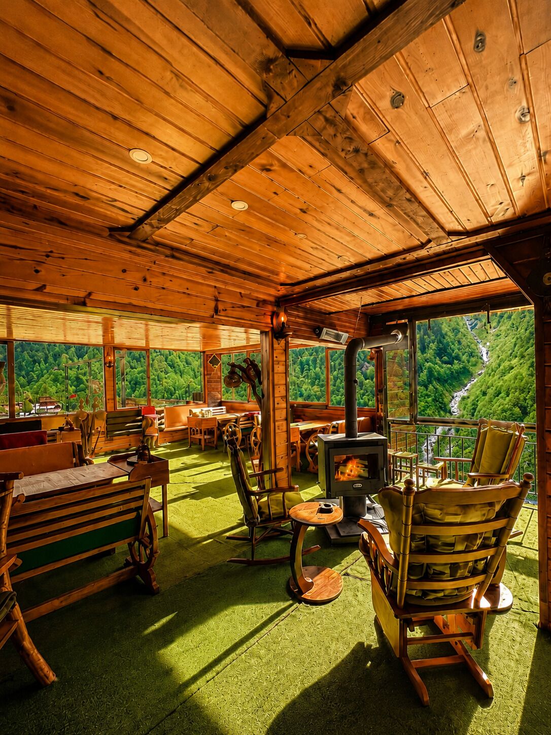 Ein gemütliches Blockhaus-Interieur mit Kamin, Holzmöbeln und weitem Blick über ein bewaldetes Tal.