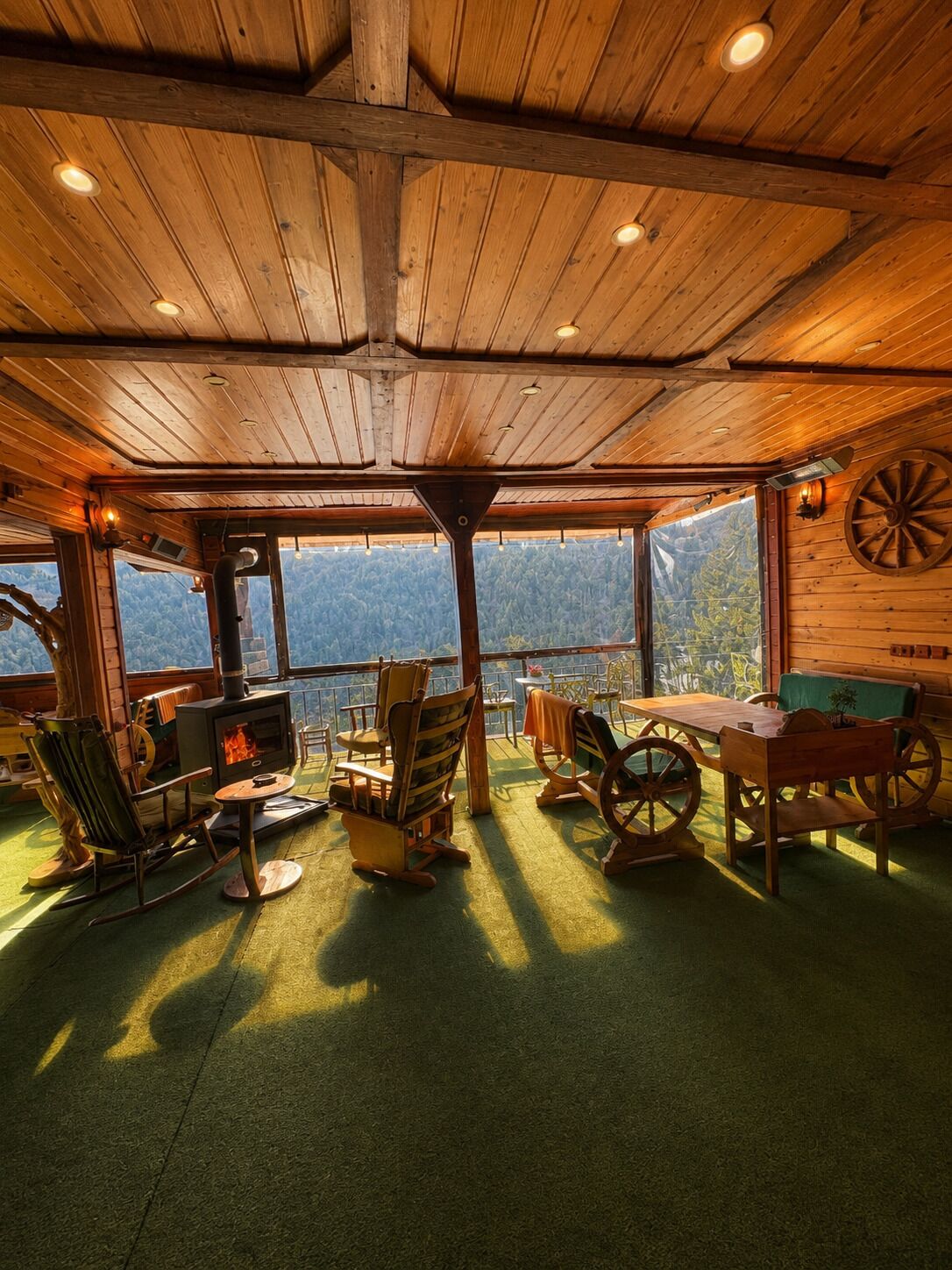 Acogedor interior de cabaña con chimenea, mobiliario de madera y una vista panorámica a la montaña.