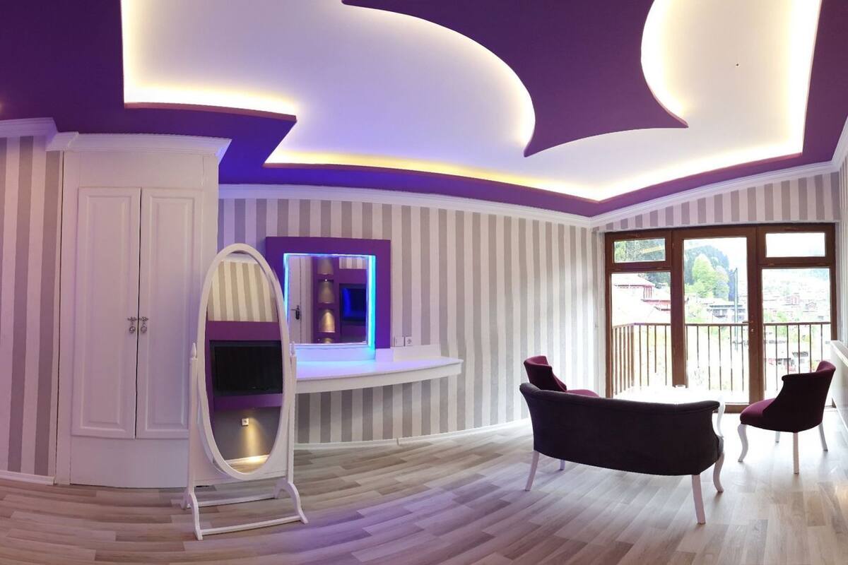 A modern bedroom with a bed, vanity, and seating area.