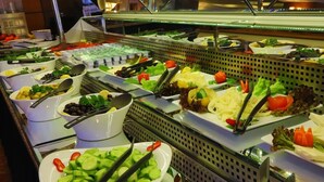 Een buffet met diverse gerechten, waaronder salades, fruit en groenten.