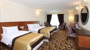 Een hotelkamer met twee bedden, een bureau, een stoel, een spiegel en een vloerbedekking.