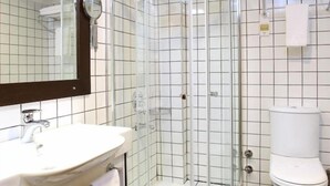Een badkamer met een douchecabine van glas, een witte wastafel en een toilet.