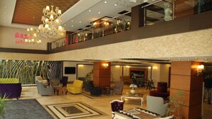 Een hotel lobby met een kroonluchter, een zithoek en een zichtbare trap.