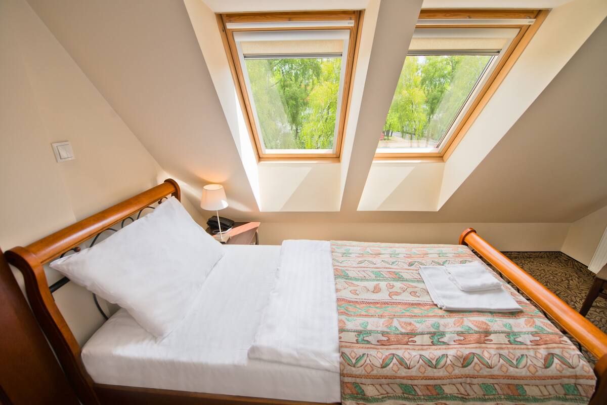 A bedroom with a bed, a nightstand, and two skylights providing natural light.