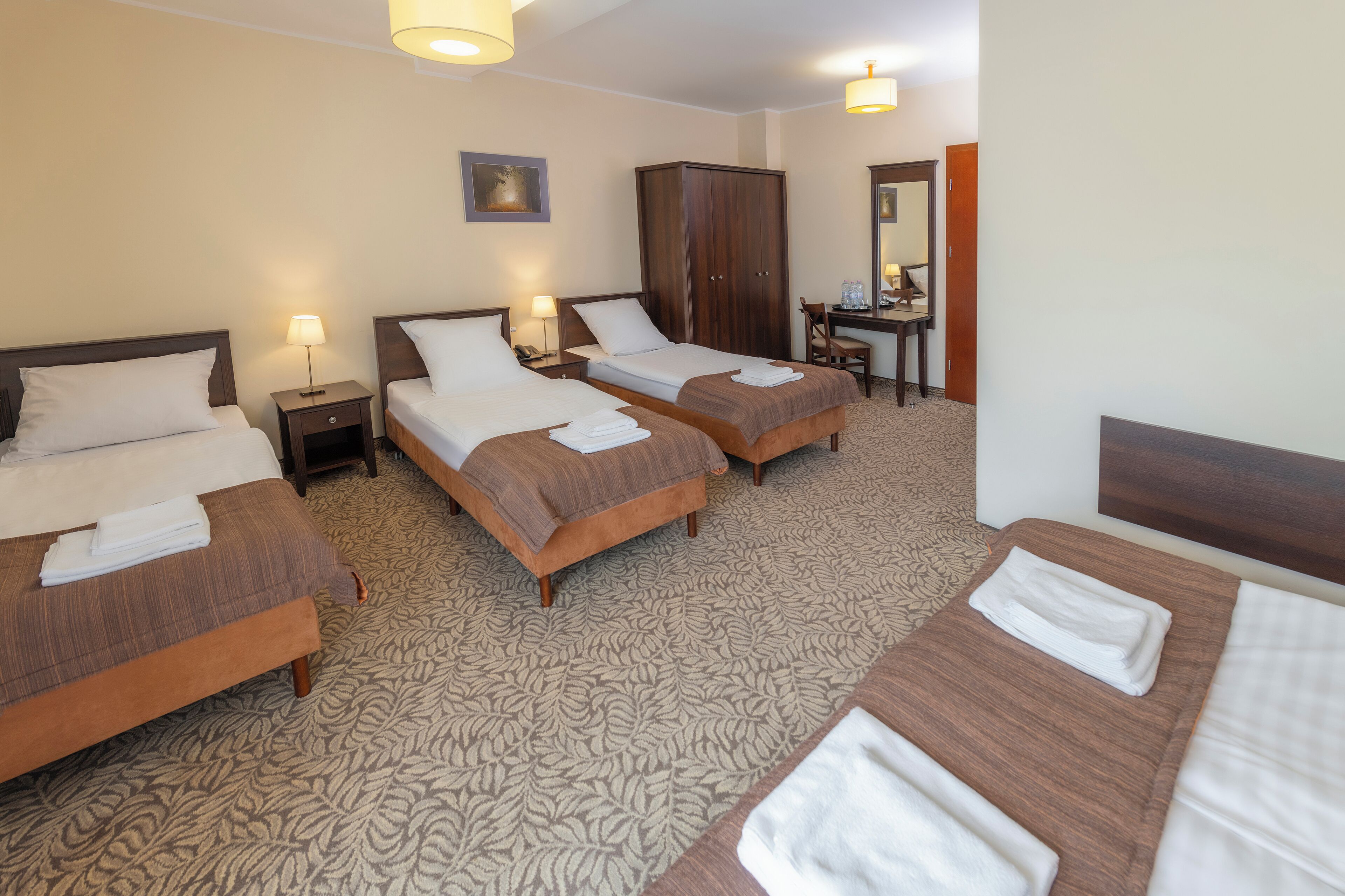 Une chambre d’h ôtel avec trois lits, un bureau et une armoire.