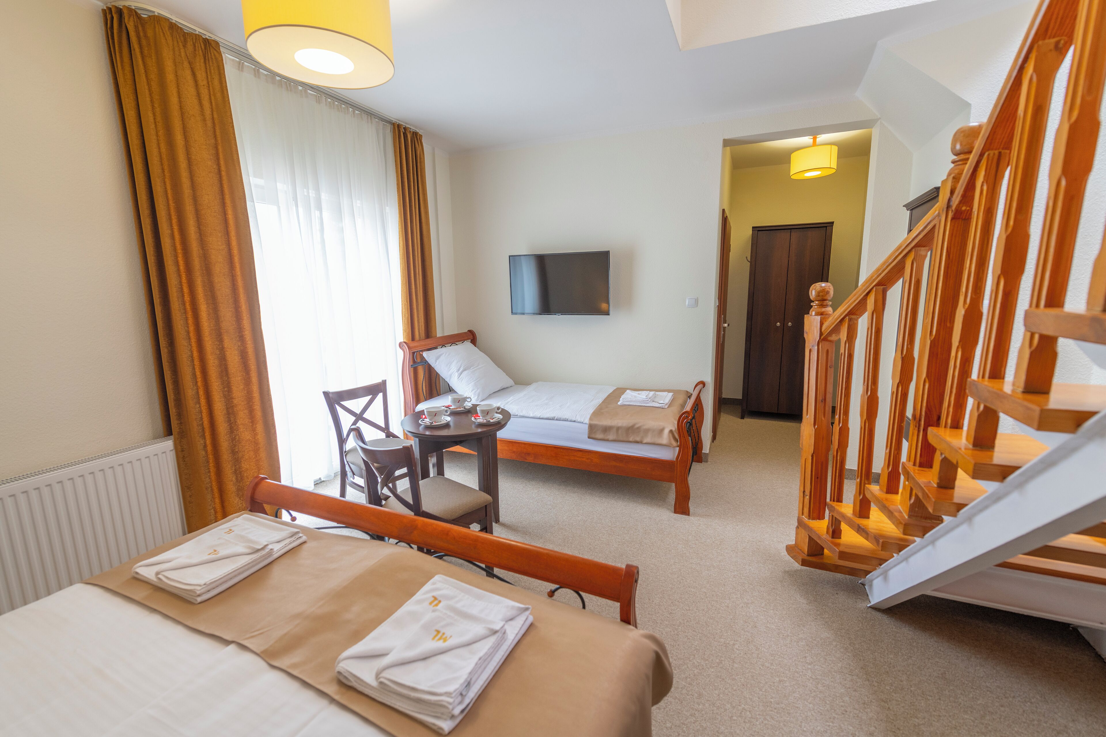 Ein Hotelzimmer mit Bett, Schreibtisch, Stuhl, Fernseher und einer Treppe.