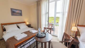 A hotel room with a bed, a small table with a tray, a chair, and a view of the outdoors.