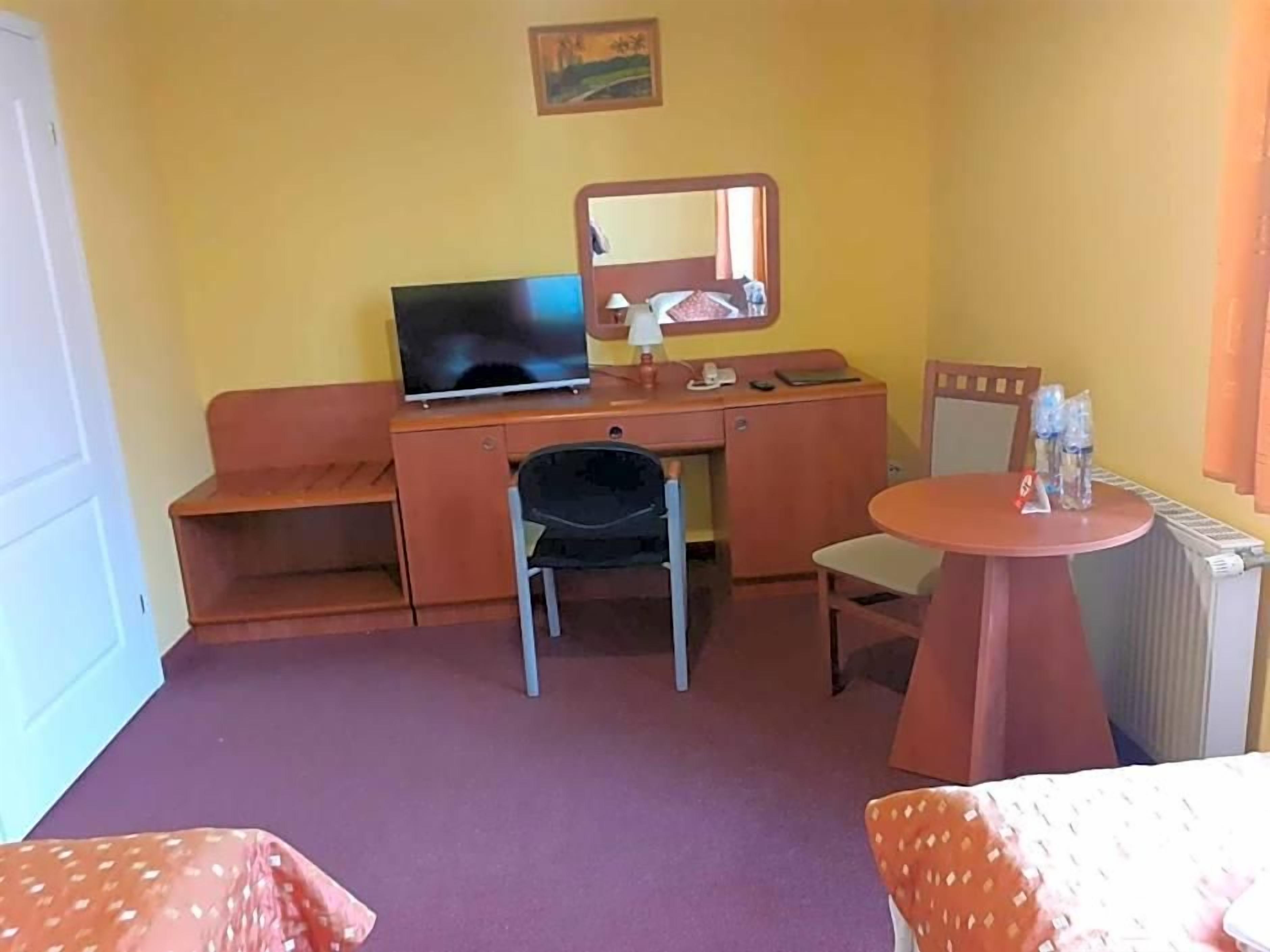 Una habitación de hotel con cama, escritorio, silla, mesa redonda y radiador.
