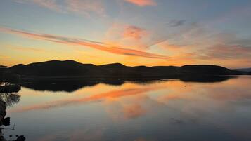 A calm lake at sunset with mountains in the background.
