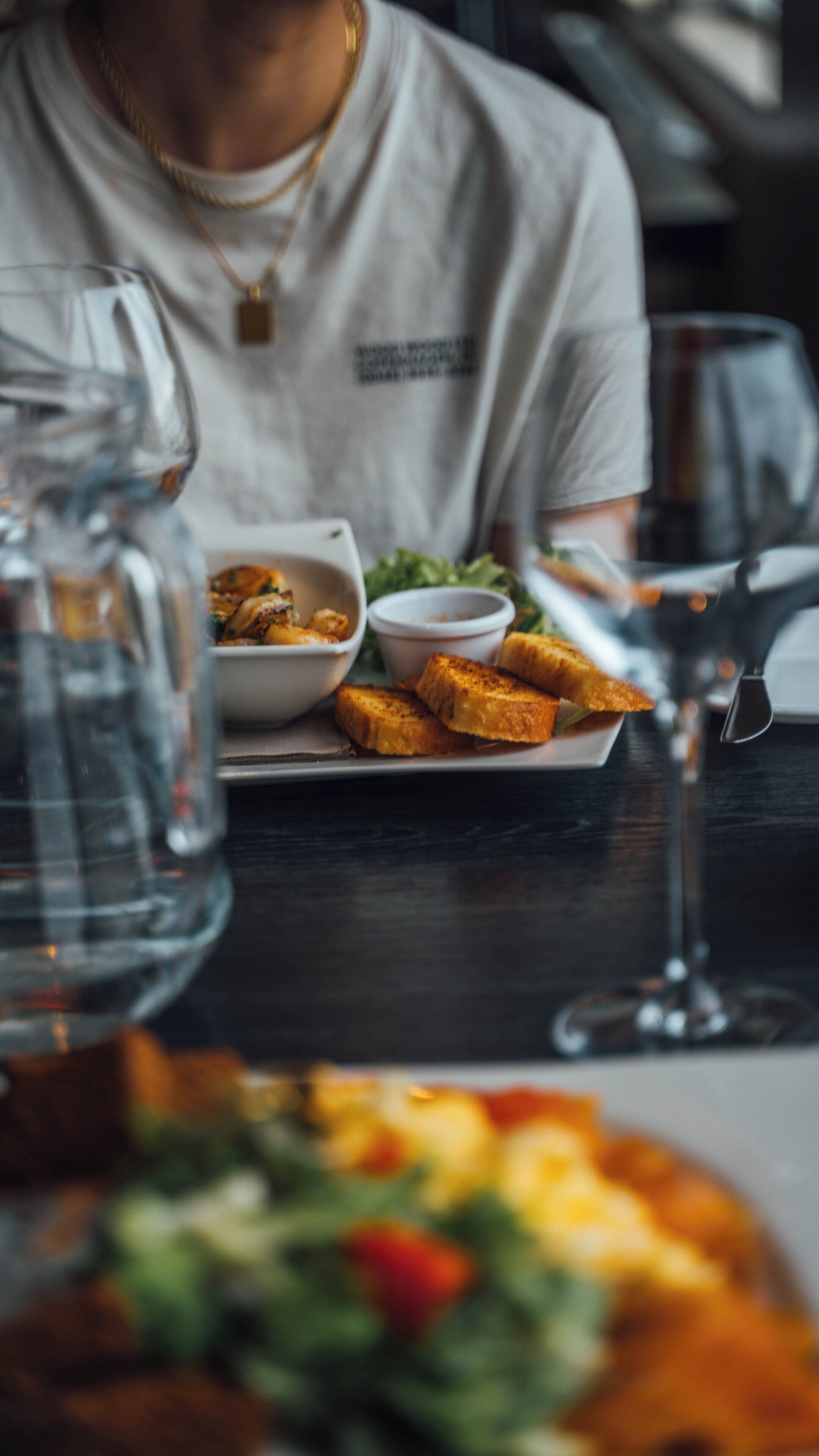 Una mesa de comedor con un plato de comida, vasos y un vaso de agua.