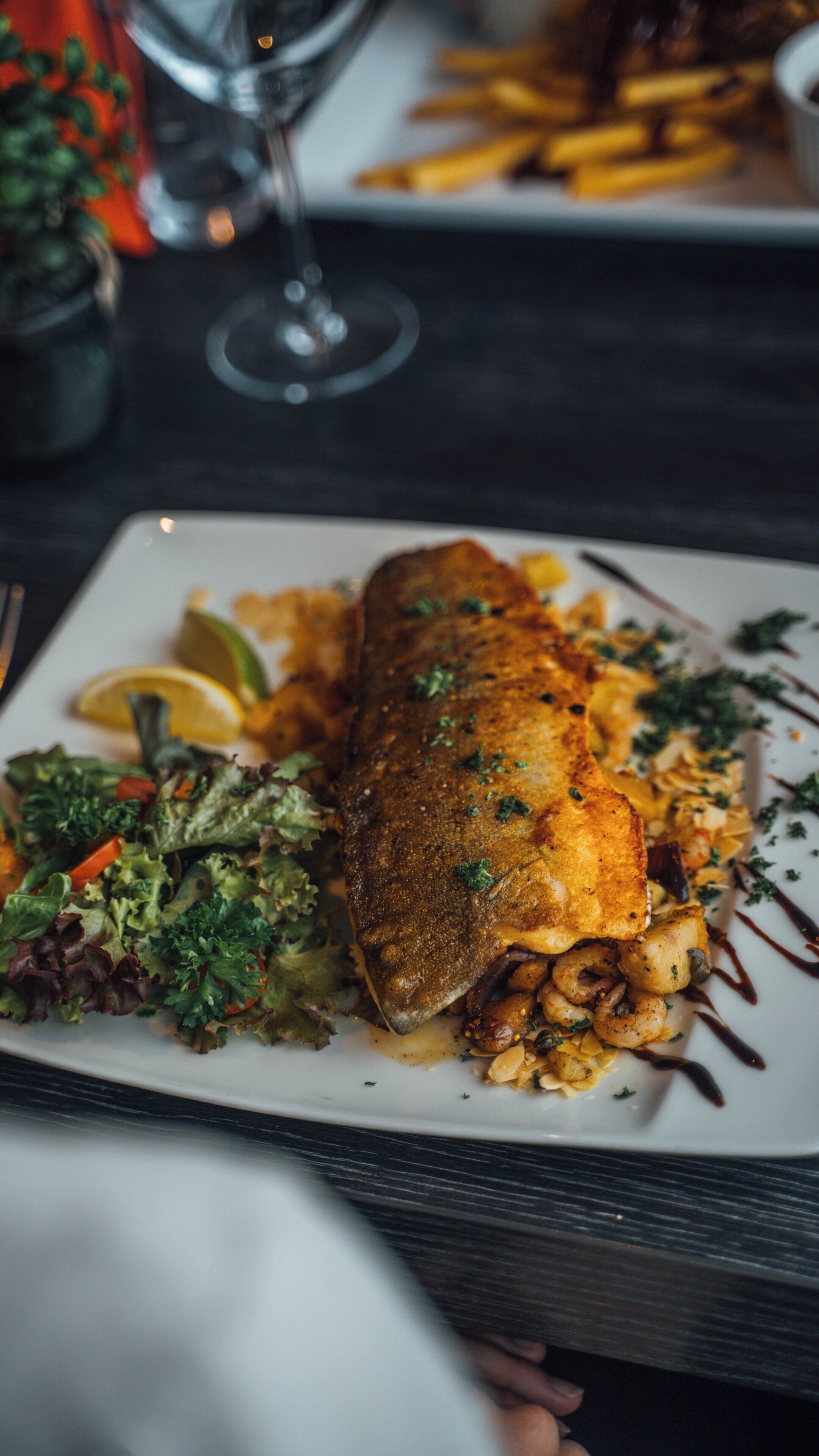 A plate of food with a fish fillet, salad, and fries.
