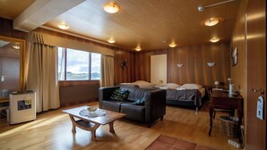 Um quarto acolhedor com teto de madeira, um sofá, uma cama, uma mesinha e uma janela com cortinas.