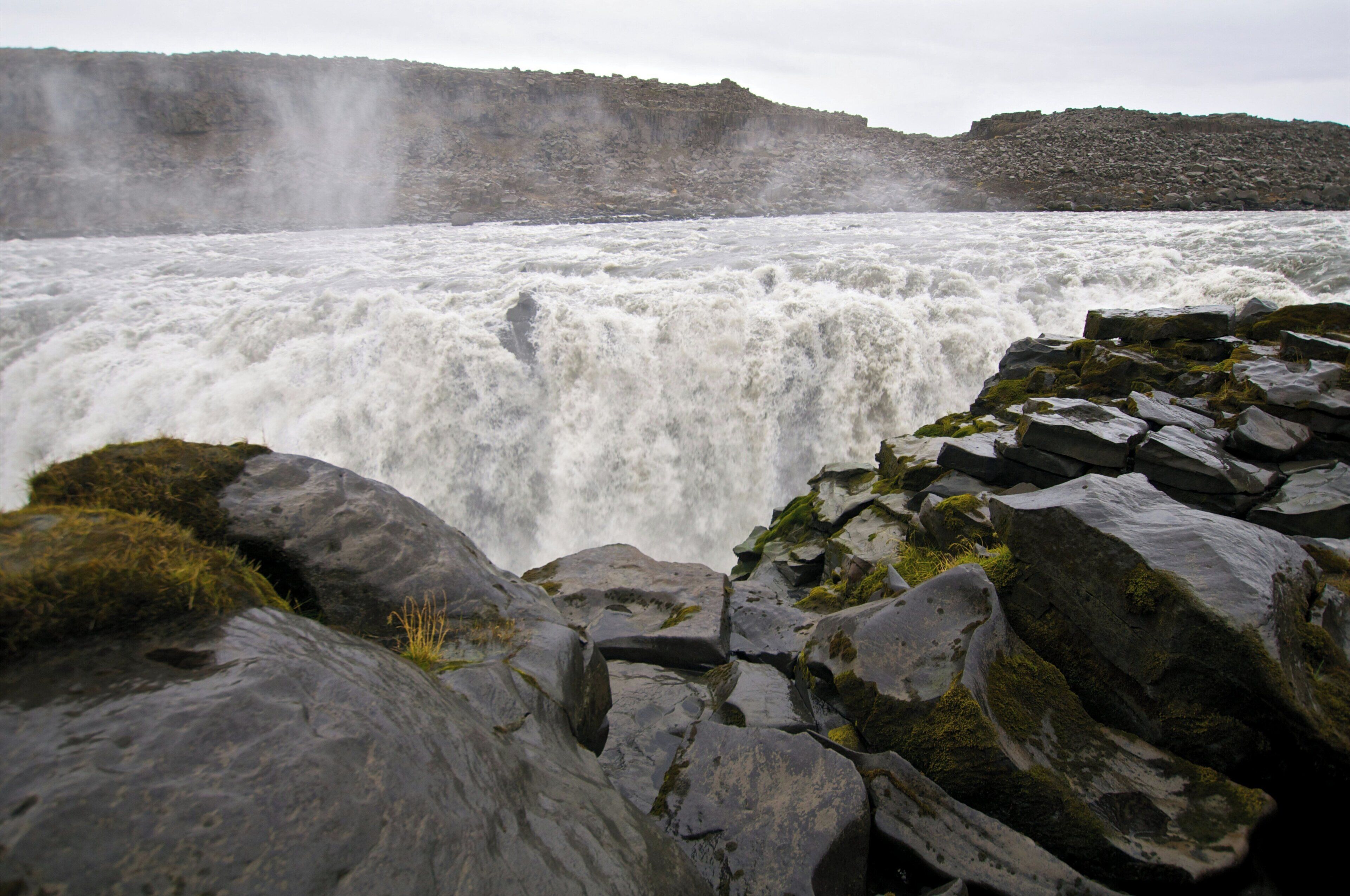 A waterfall surrounded by large rocks and moss.