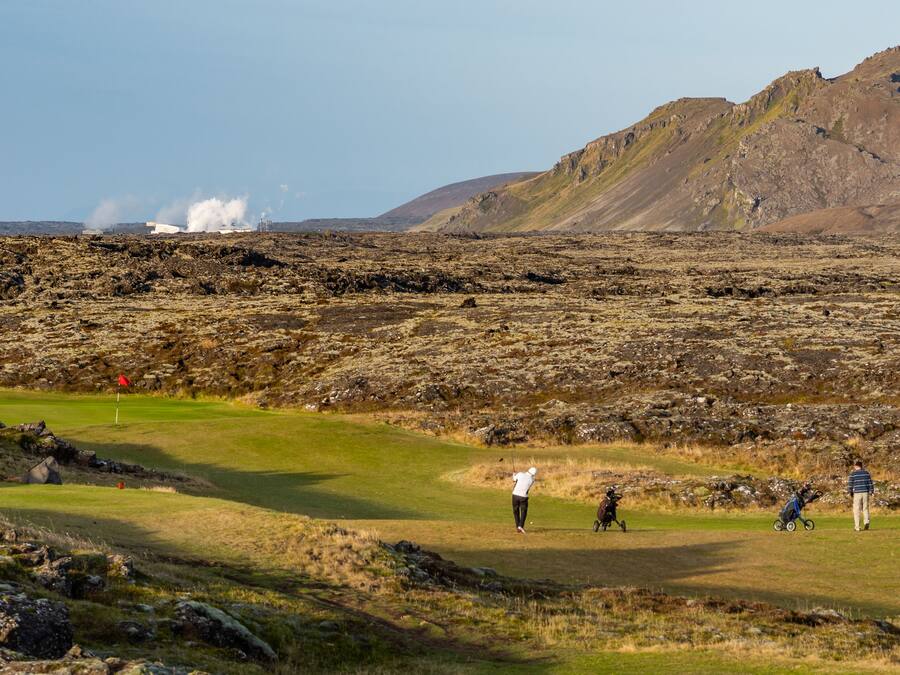 A golf course with a rocky terrain and a mountain in the background.