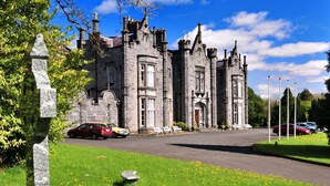 A historic stone building with a large driveway and parked cars. - Belleek Castle (Ballina)