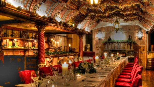 A long dining table set with red velvet chairs, candles, and fine china. - Belleek Castle (Ballina)