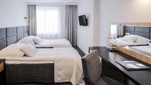 A hotel room with two beds, a desk, a chair, a TV, and a large window with curtains. - Hotel Sport (Belchatow)