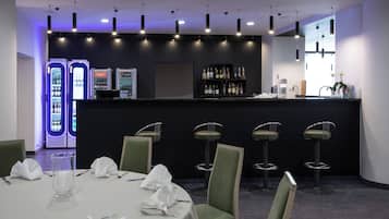 Um restaurante com área de bar, banquetas e uma mesa posta para refeição.