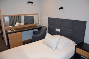 A hotel room with a bed, a desk, a chair, a mirror, and a nightstand. - Hotel Sport (Belchatow)