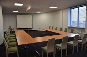 A conference room with a long table, chairs, a projector screen, and a window with blinds. - Hotel Sport (Belchatow)