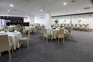 A conference room with multiple tables and chairs, a bar area, and a white ceiling with recessed lighting. - Hotel Sport (Belchatow)