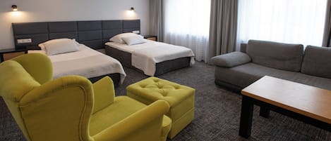 A hotel room with two beds, a sofa, a yellow armchair, and a small table.
