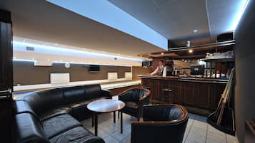 Una zona de bar con asientos de cuero, una barra y una pantalla de televisión.