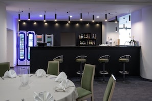 A restaurant with a bar area, bar stools, and a table set for dining. - Hotel Sport (Belchatow)