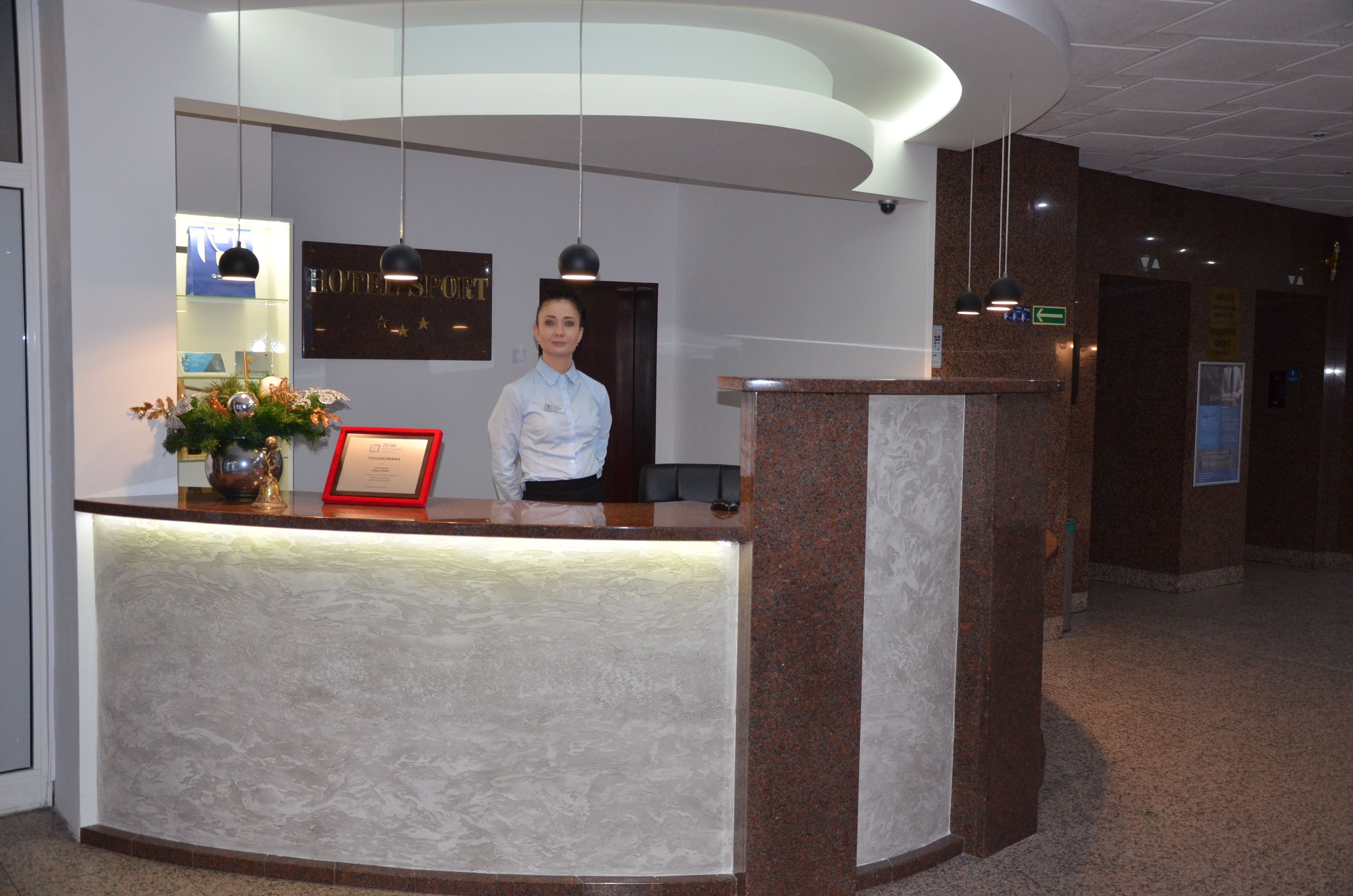 A hotel reception desk with a modern design, a framed certificate, and a decorative vase.