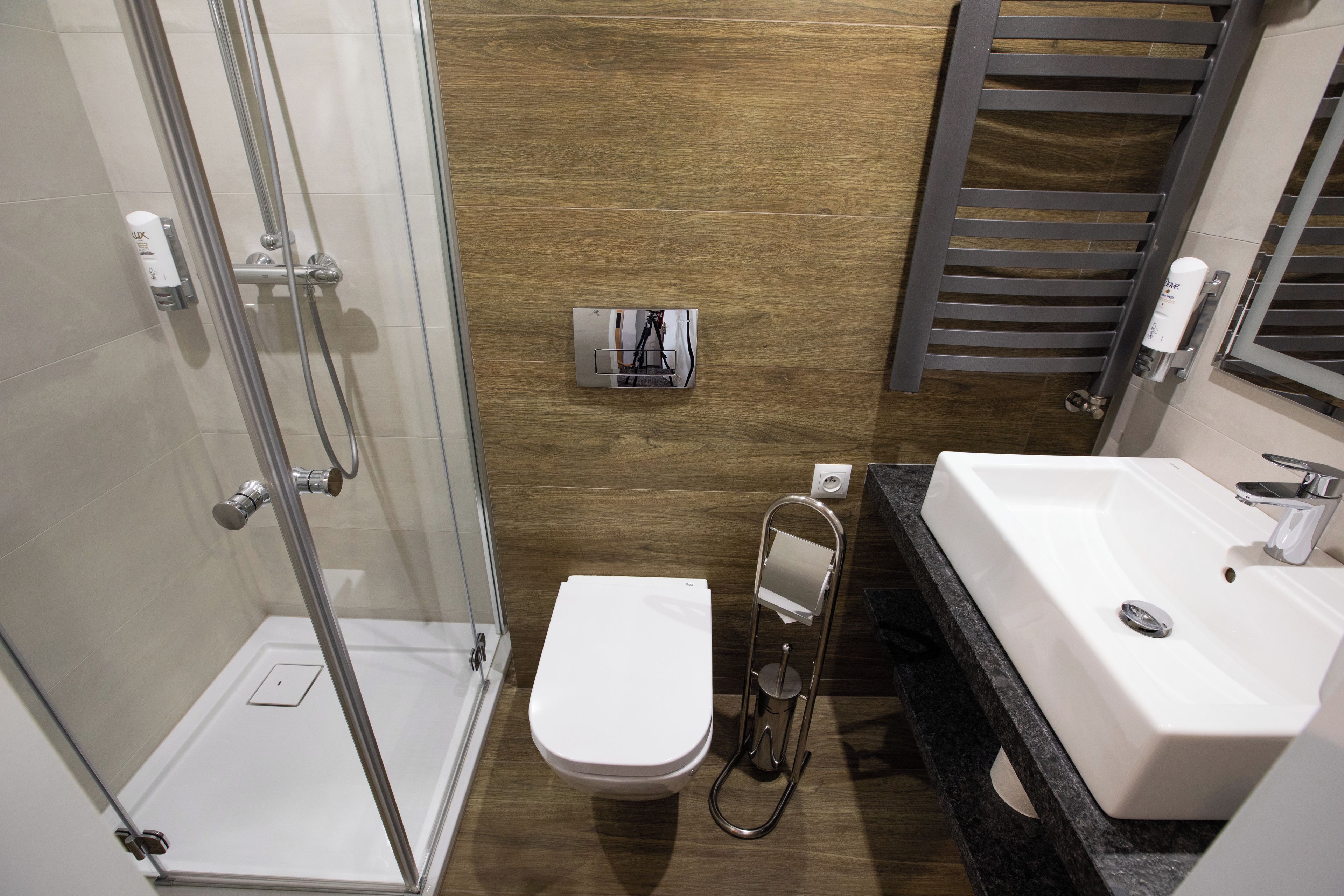 Een moderne badkamer met een douchecabine van glas, een wit toilet en een wastafel met spiegel.
