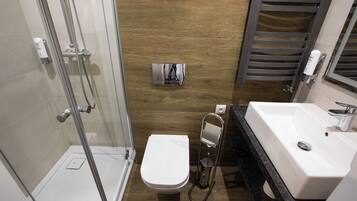 Een moderne badkamer met een douchecabine van glas, een wit toilet en een wastafel met spiegel.