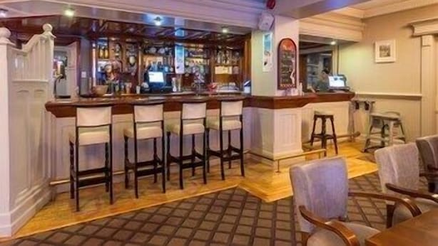 A bar area with a counter, multiple bar stools, and a patterned floor. - Lake Of Shadows (Buncrana)