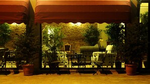 Une terrasse extérieure avec un mur en pierre, des plantes en pot et du mobilier d’extérieur.