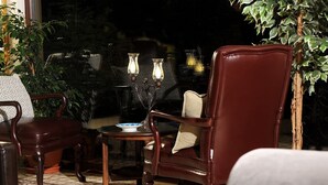 Un espace patio aménagé avec deux fauteuils en cuir, une petite table et un vase décoratif contenant des bougies.