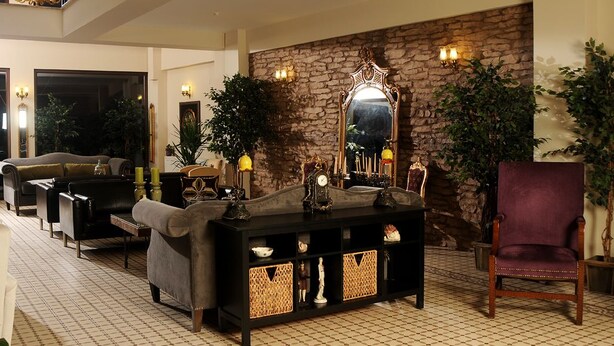 Un hall d’entrée avec un mur en pierre, un grand miroir, une console ornée d’objets décoratifs, un fauteuil moelleux et une chaise en bois.