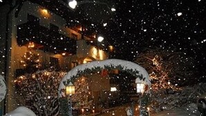 Una entrada nevada con un arco decorativo y ventanas iluminadas, que evoca un ambiente invernal.