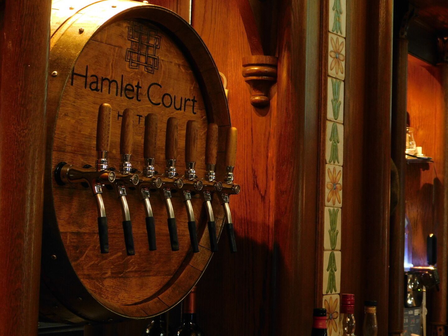Un barril de madera con la etiqueta 'Hamlet Court' y varias llaves, indicando un ambiente de bar o pub.