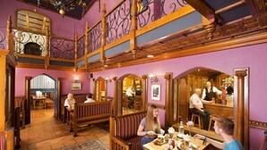 A restaurant with wooden benches and tables, a bar area, and a high ceiling with decorative ironwork. - Hamlet Court Hotel (Johnstown Bridge)