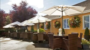 An outdoor patio area with wicker furniture and white umbrellas. - Hamlet Court Hotel (Johnstown Bridge)