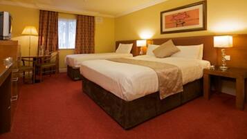 A hotel room with two beds, a desk, a chair, and a television.