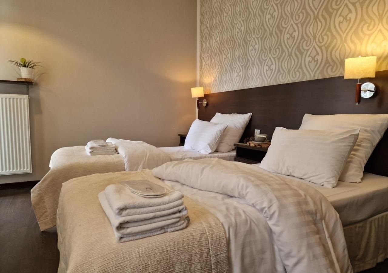 A hotel room with two beds, each with a headboard, and bedside lamps.