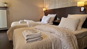 A hotel room with two beds, each with a headboard, and bedside lamps.
