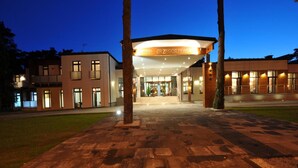 A modern hotel entrance with a covered walkway, a clear sky, and a well-lit facade.