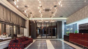 A modern lobby with a patterned ceiling, a red sofa, and a reception desk.