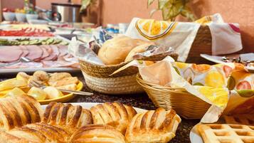 Una mesa de buffet con diversos alimentos, incluyendo pasteles, pan y frutas.