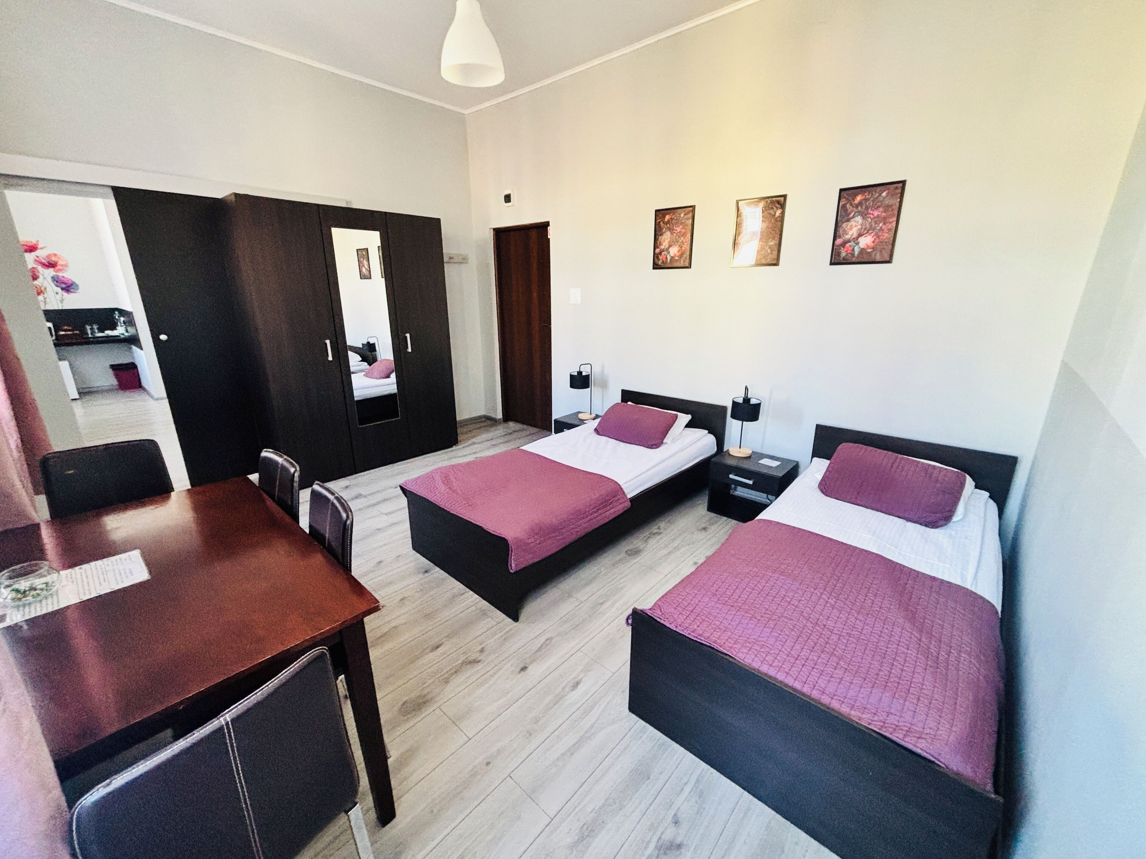 Habitación de hotel con dos camas, un escritorio y una silla. Hay tres cuadros en la pared.