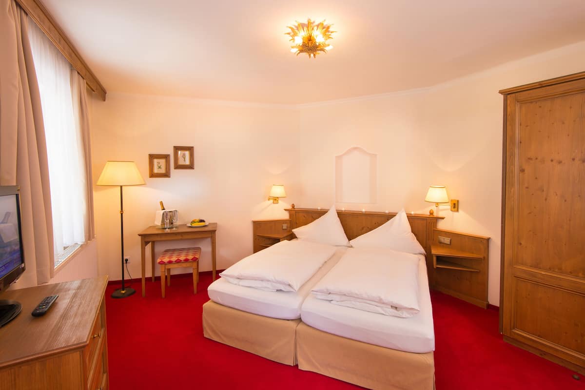 Une chambre d’hôtel comprenant un lit, des tables de chevet, des lampes, un bureau avec un ordinateur et une armoire.