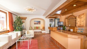 A spacious living area with a reception desk, seating arrangements, and a large plant. - Hotel Dachstein (Filzmoos)