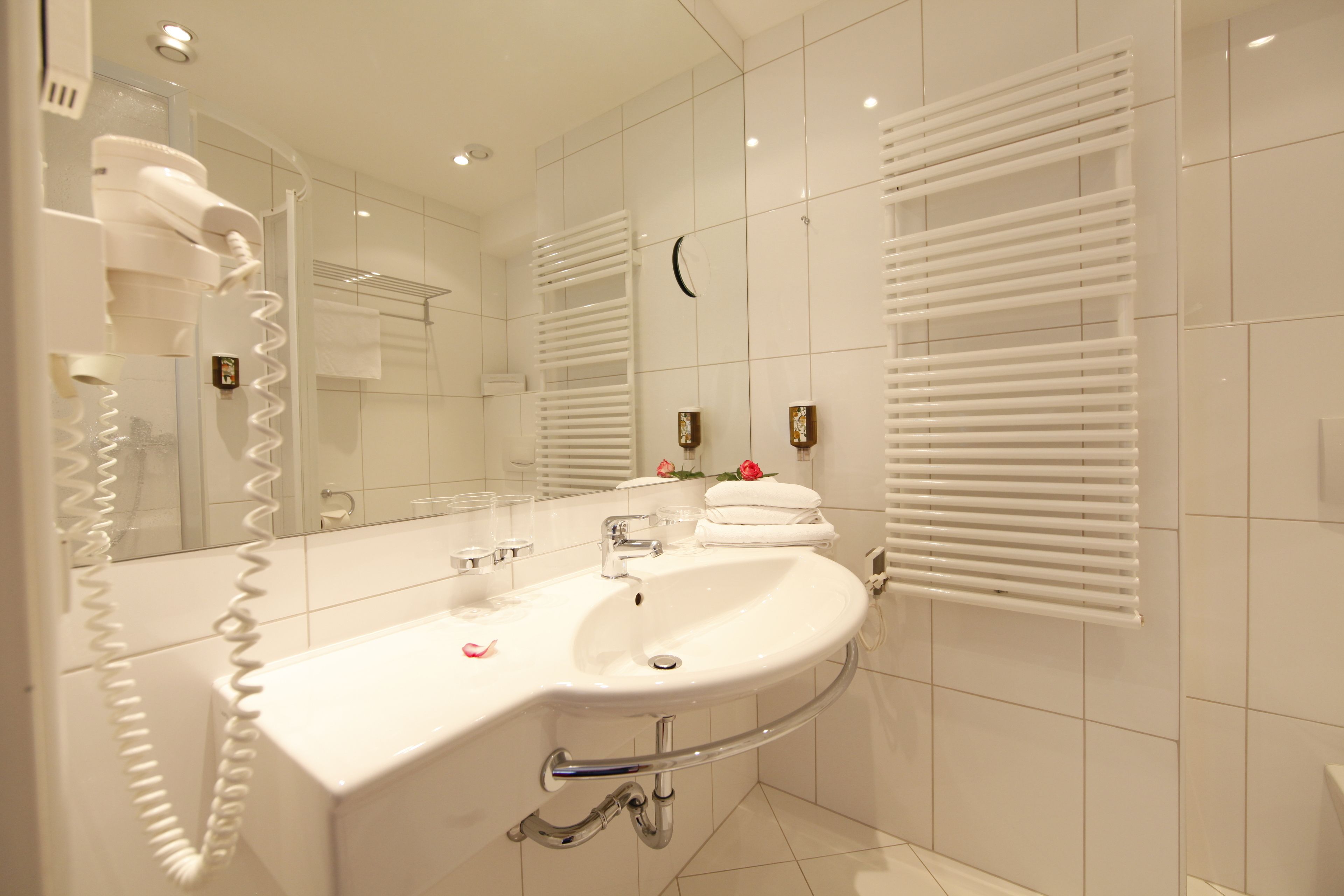 A modern bathroom with a white sink, mirror, and towel rack.