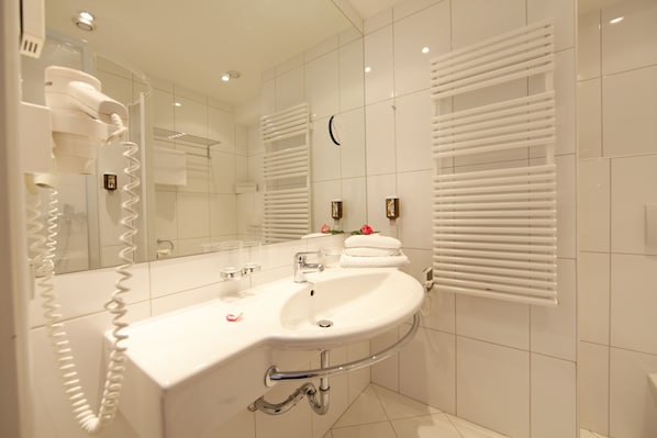 Un baño moderno con lavamanos, espejo y toallero blancos.